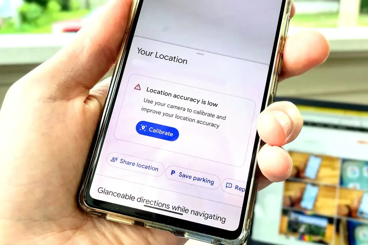 Dłoń trzyma telefon z komunikatem o niskiej dokładności lokalizacji. Widoczny jest przycisk 
