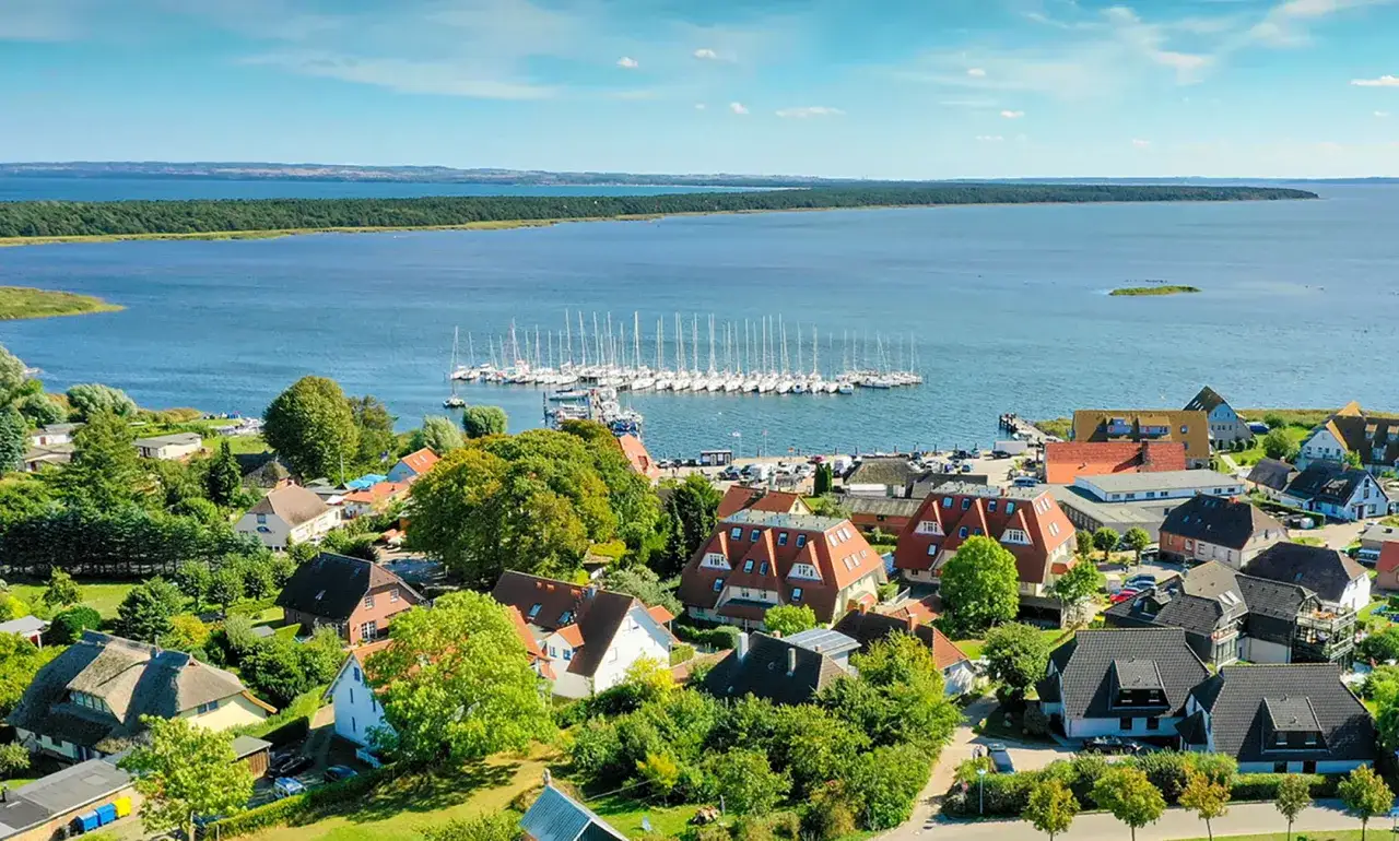 Breege Hafen mit vielen Segelbooten im Wasser, umgeben von grünen Bäumen und roten Dächern.