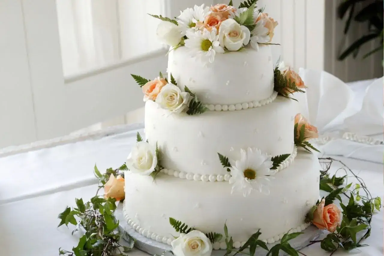 Elegancki tort weselny z kremowymi różami i margaretkami. Wyobraź sobie jego wyborne tort weselny smaki!