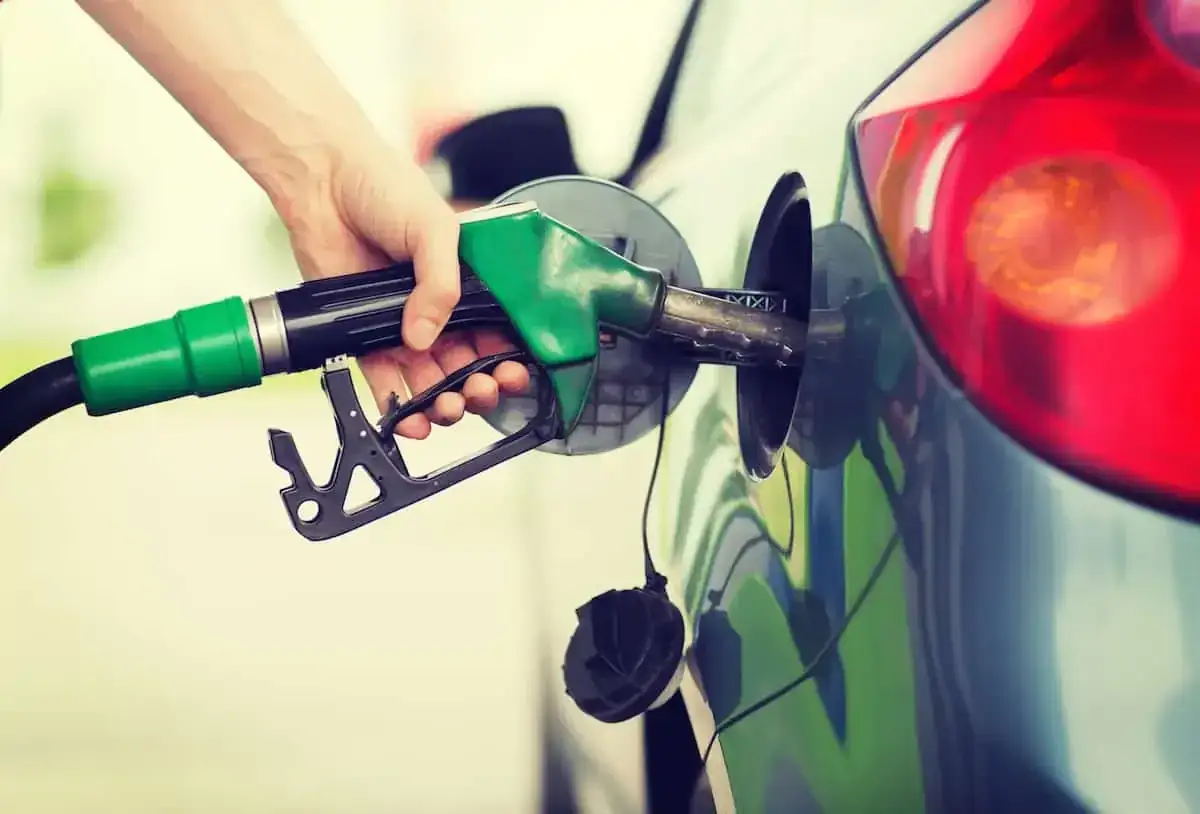 Mano che inserisce la pompa di benzina nel serbatoio di un'auto. Attenzione a non mettere benzina nel diesel!