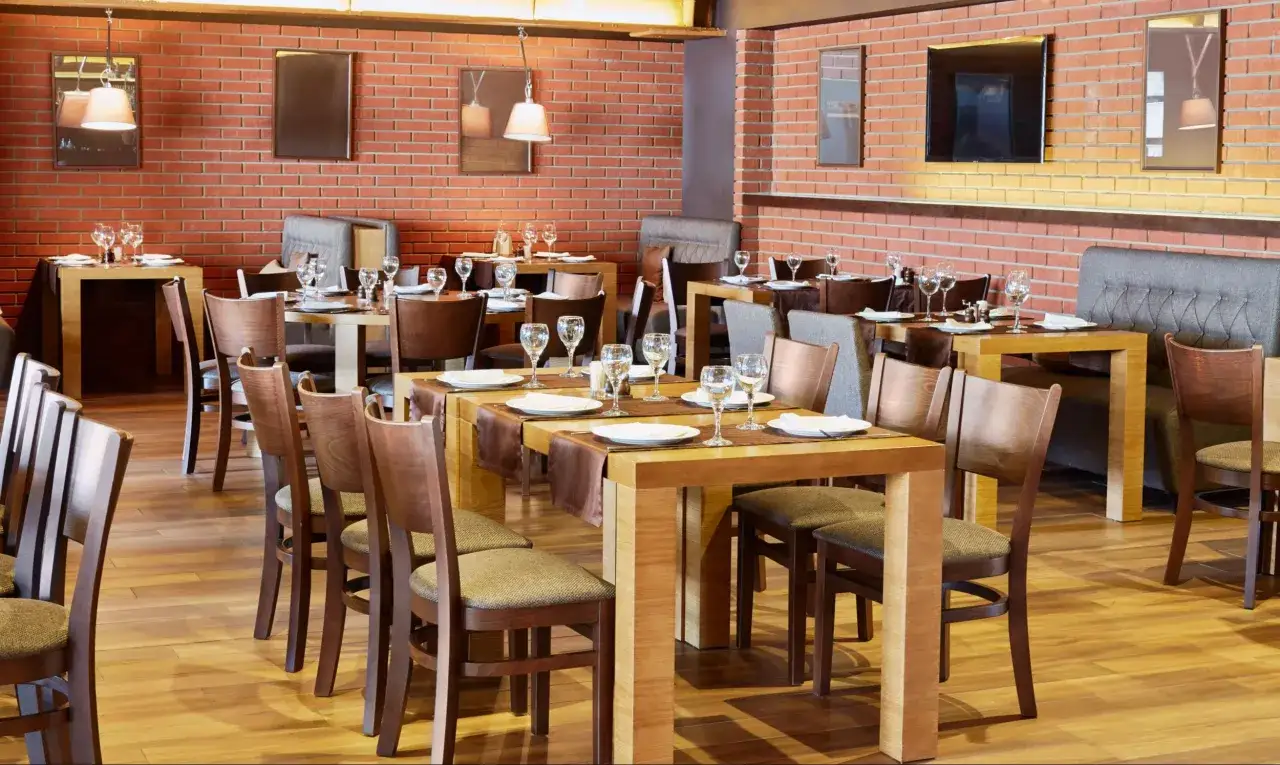 Elegancka restauracja z ceglanymi ścianami, drewnianymi stołami i krzesłami. To idealne miejsce na spotkanie w ramach branży horeca.