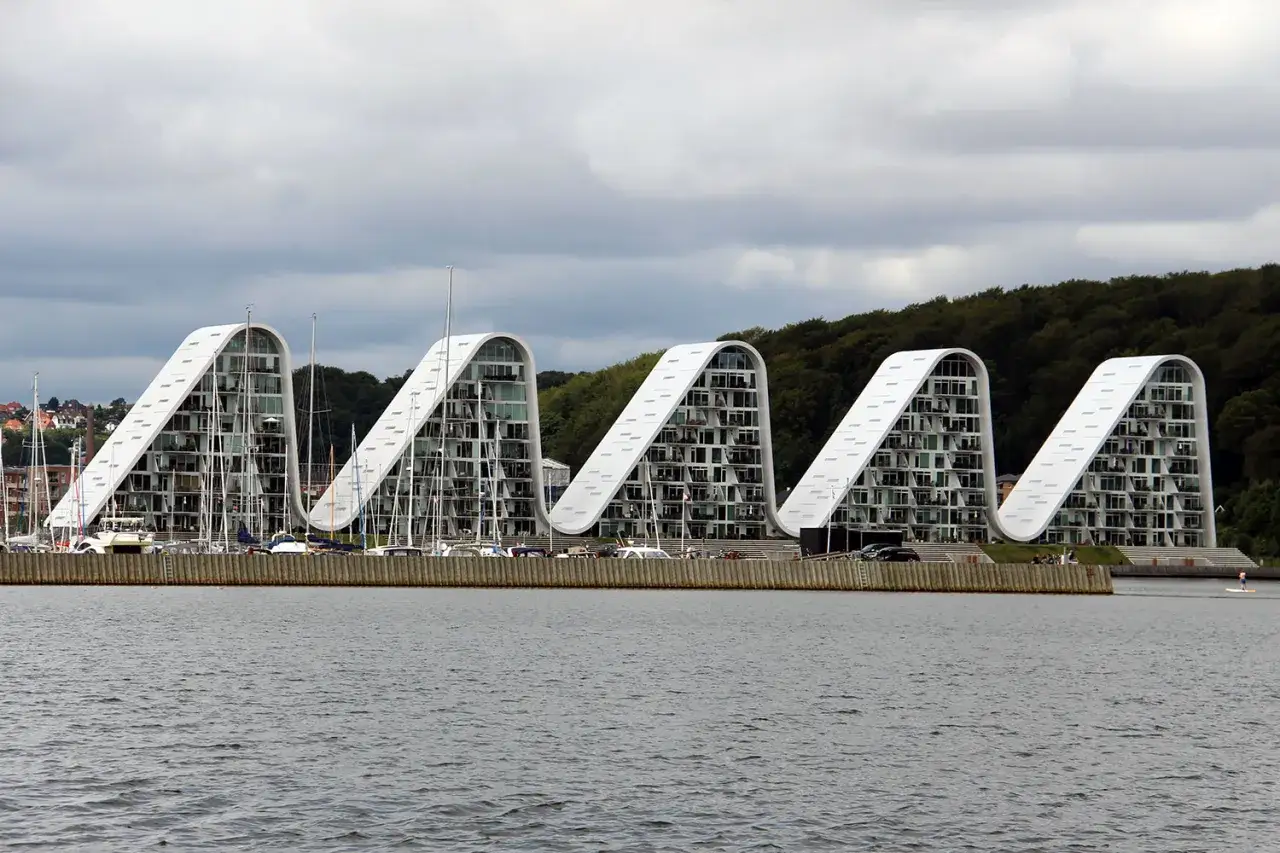 V&aring;gformade byggnader vid vattnet i Vejle, Danmark, med segelb&aring;tar i hamnen.