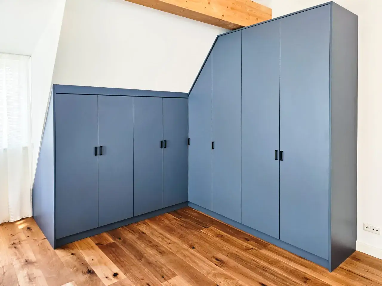 Große, blaue Einbauschränke in einem modernen Raum mit Holzboden. Sie bieten viel Stauraum, was bei der **Kleidung** und dem **Konsum** relevant ist, wenn man **Statistiken** zur Aufbewahrung betrachtet.