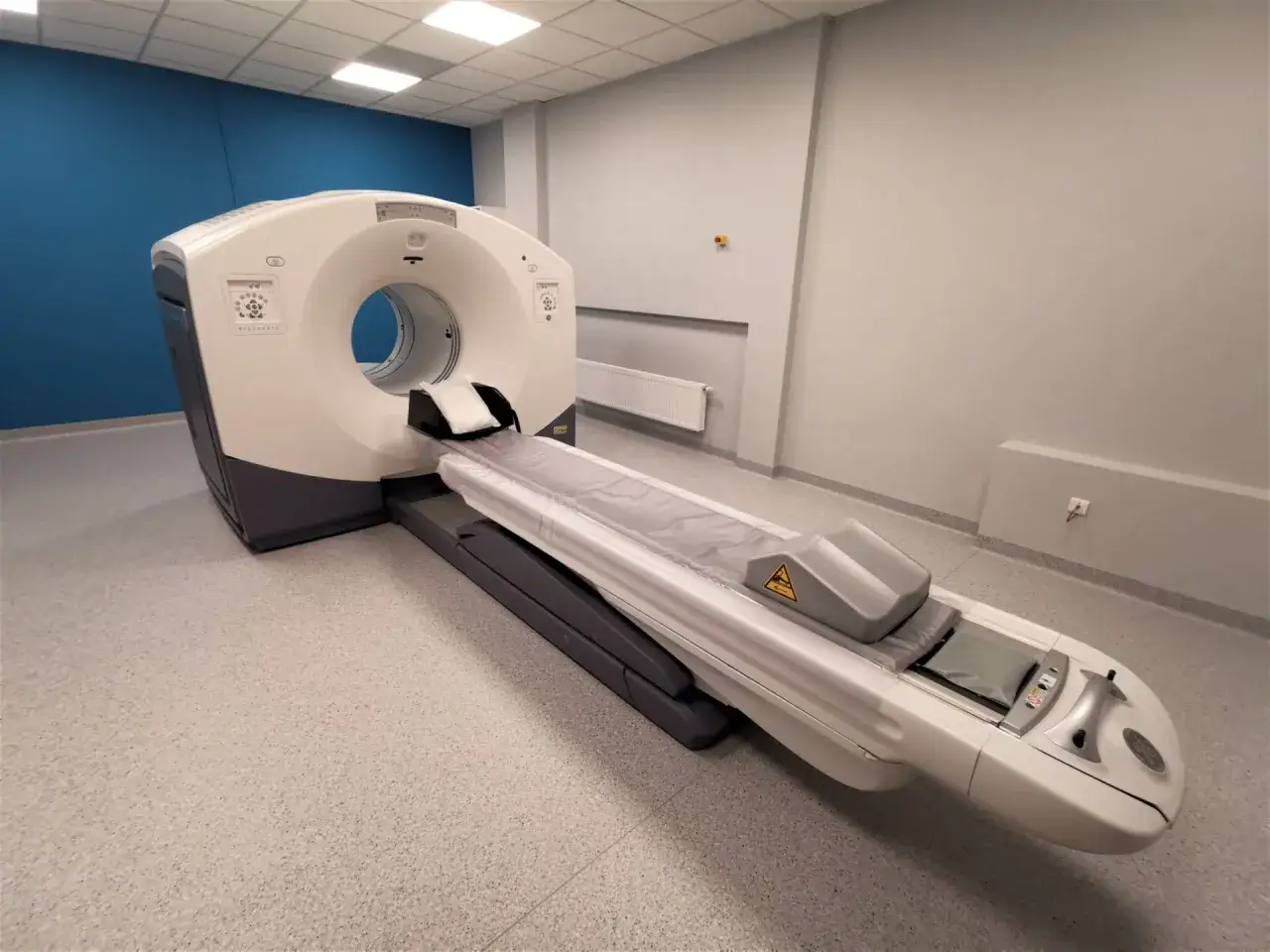 Nowoczesny aparat PET w gabinecie diagnostycznym. Widok pokazuje, jak wygląda badanie PET, z leżanką pacjenta i pierścieniem skanującym.