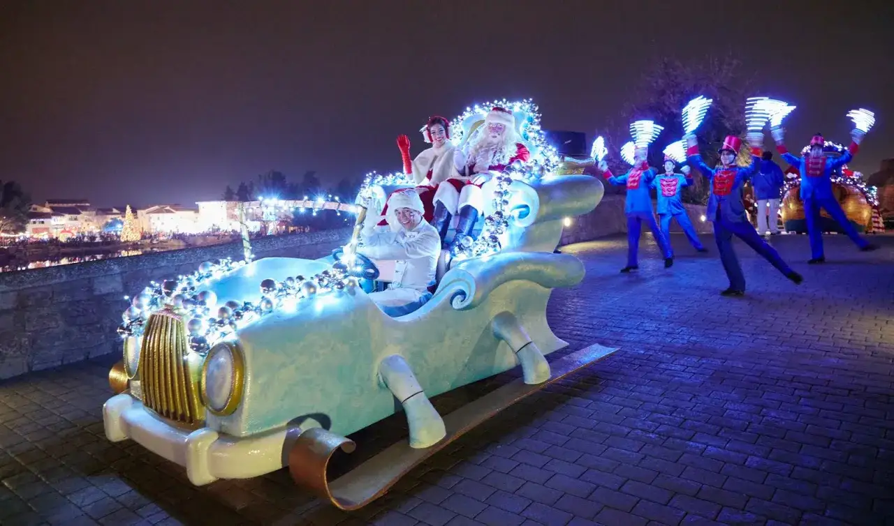 Papá Noel y sus ayudantes desfilan en un trineo-coche iluminado en PortAventura en Navidad.