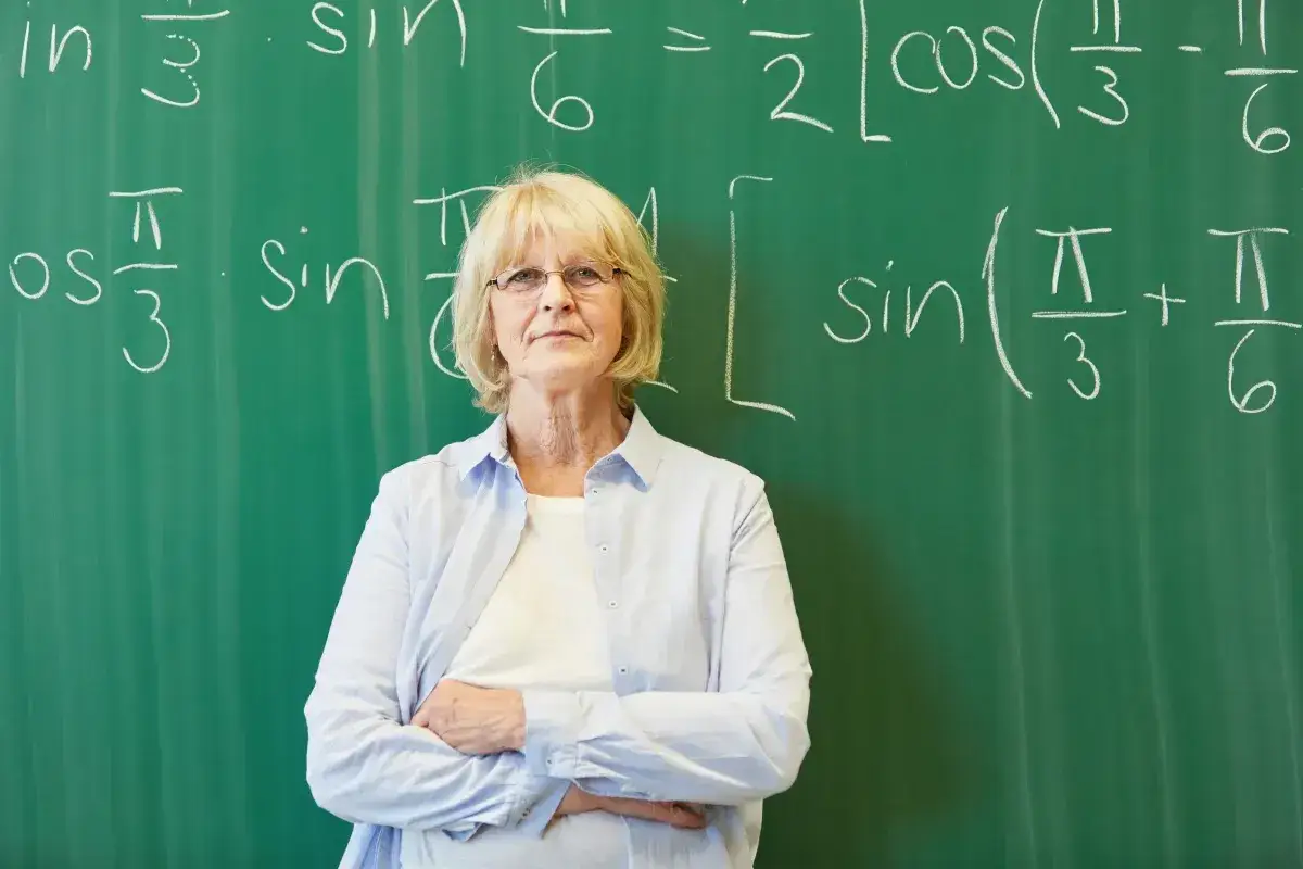 Nauczycielka matematyki przed tablicą z równaniami, symbolizująca nagrodę jubileuszową nauczycieli.