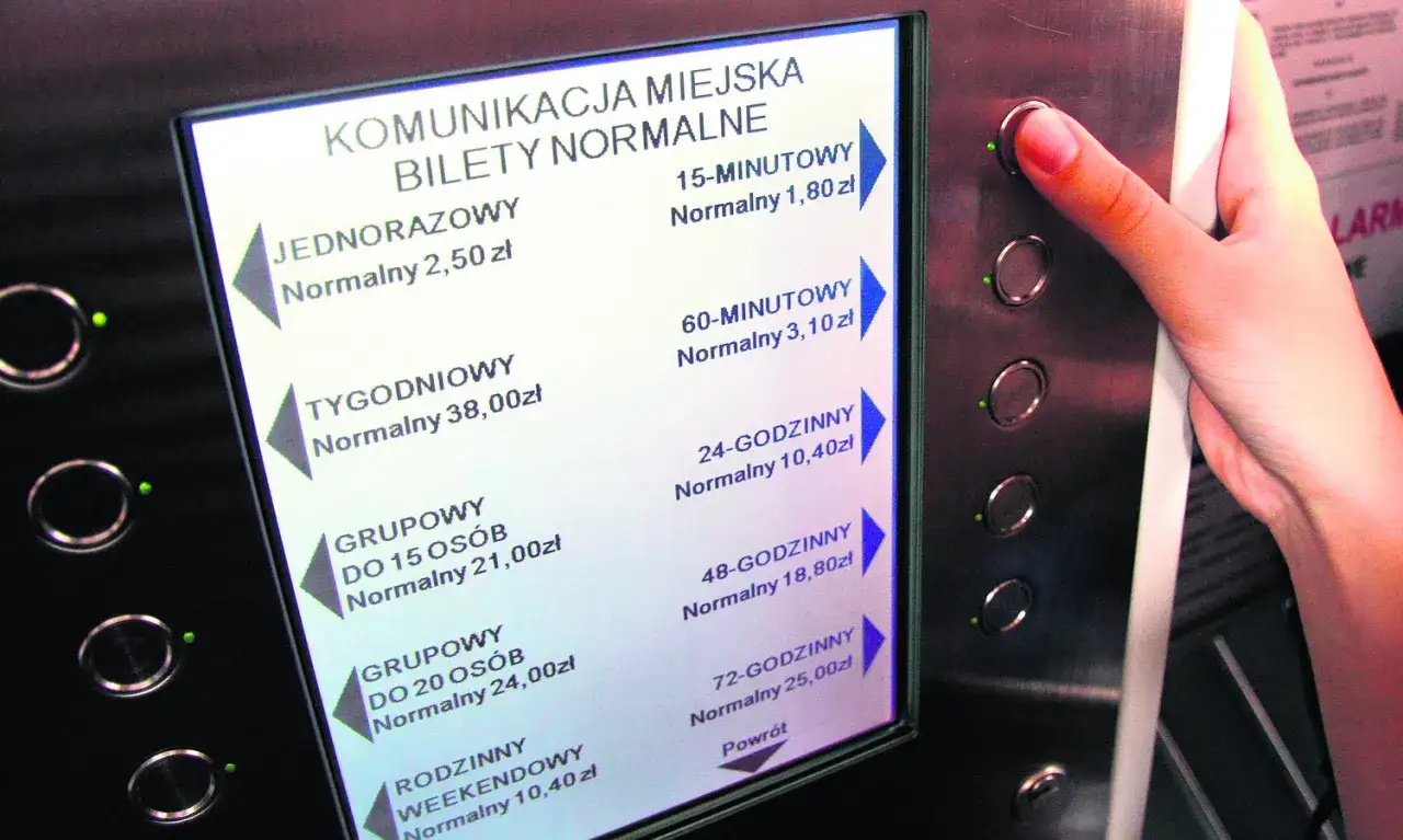 Cennik biletów komunikacji miejskiej. Wybór biletu zapobiega mandatowi za brak biletu. Dłoń naciska przycisk.
