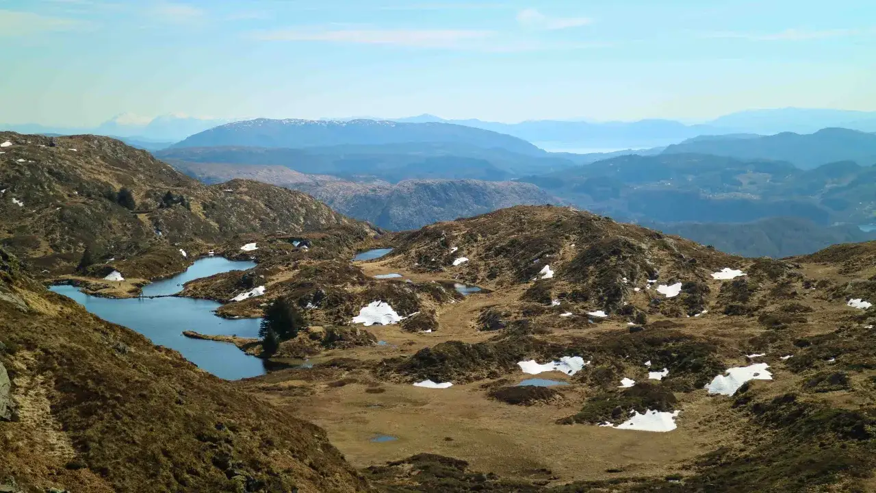 Vacker utsikt över Ulriken i Bergen med små sjöar och snöfläckar på bergssluttningarna.