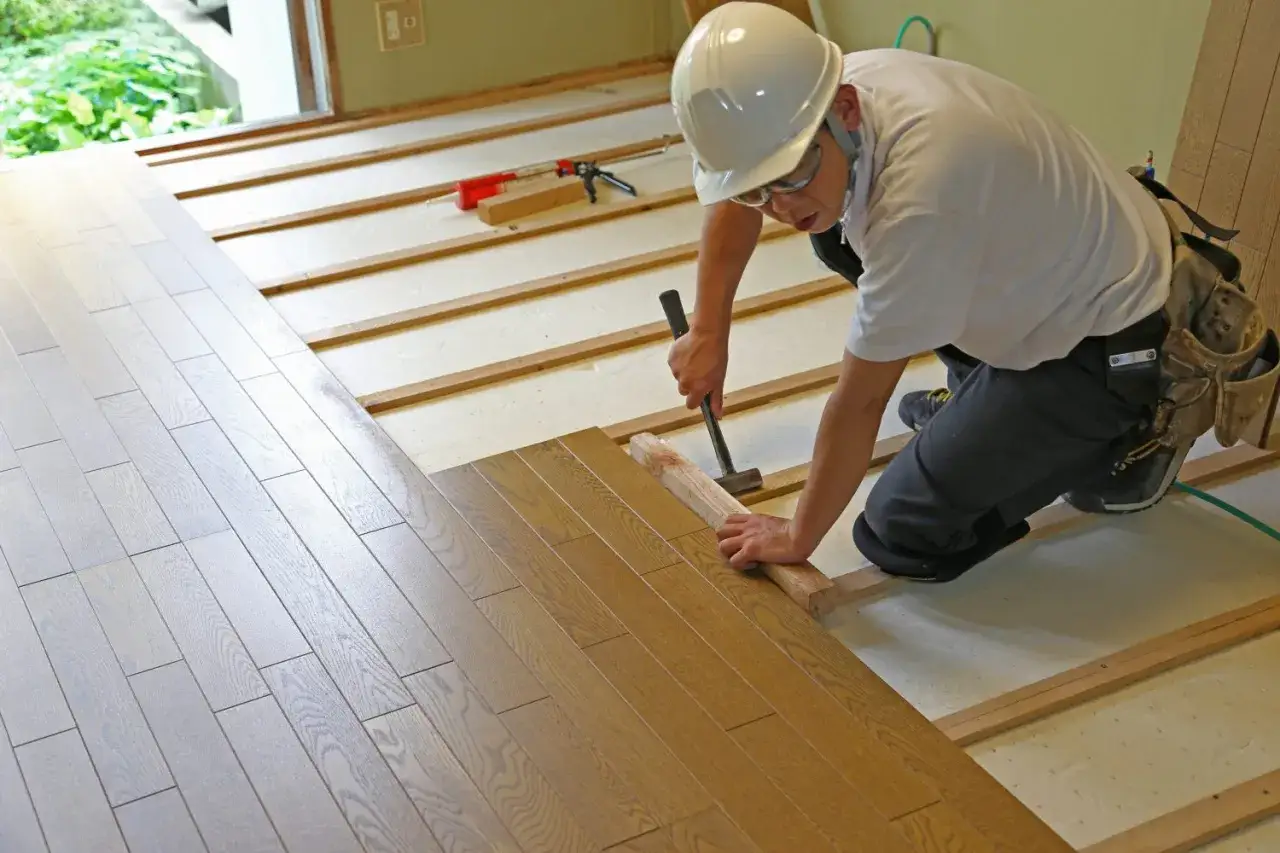 Operaio posa parquet su strato di materiali fonoisolanti, creando un ambiente confortevole e silenzioso.