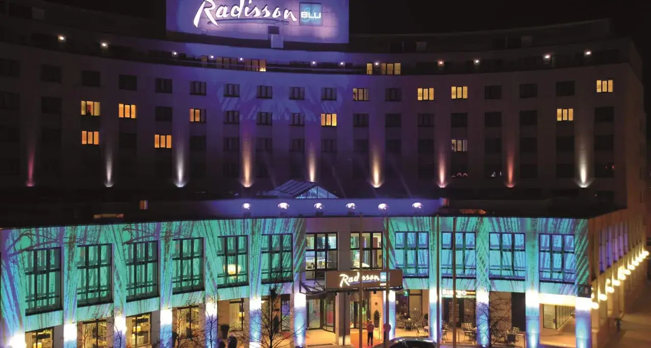 Elegancki hotel Radisson Blu Cottbus nocą, oświetlony kolorowymi projekcjami i światłami.
