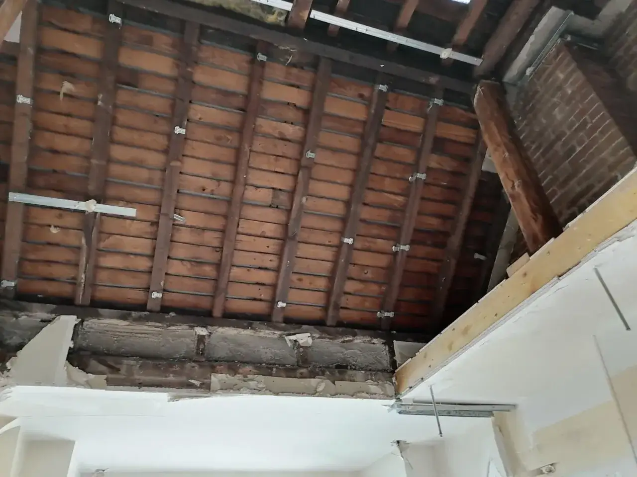 Travaux de renfort sur une panne de charpente en bois, avec des &eacute;querres m&eacute;talliques et des tasseaux.