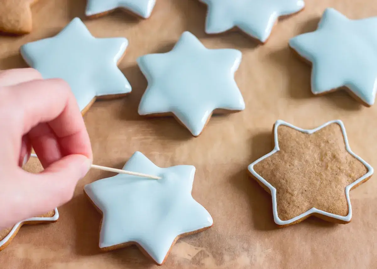 Mano decora galletas de jengibre con glaseado azul claro.