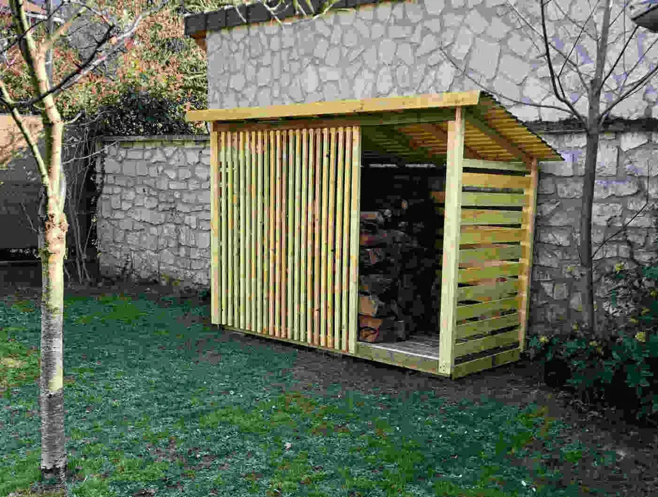 Abri en bois pour stocker du bois de chauffage, avec une façade à claire-voie en orme.