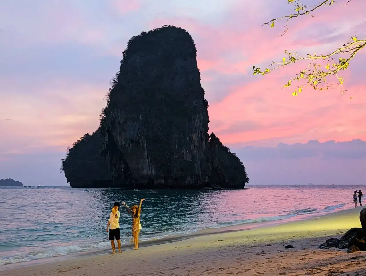 Para zakochanych cieszy się zachodem słońca na Ao Nang Beach. W tle majestatyczna skała i różowe niebo.