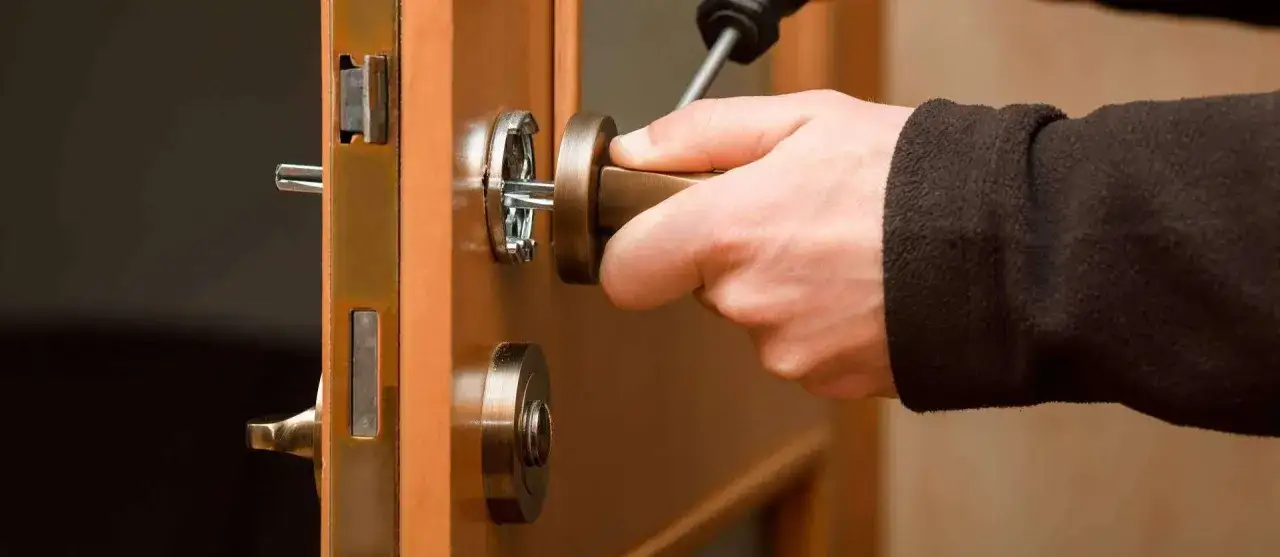 Mano girando la llave para cambiar cerradura puerta. Mecanismo de seguridad en madera.