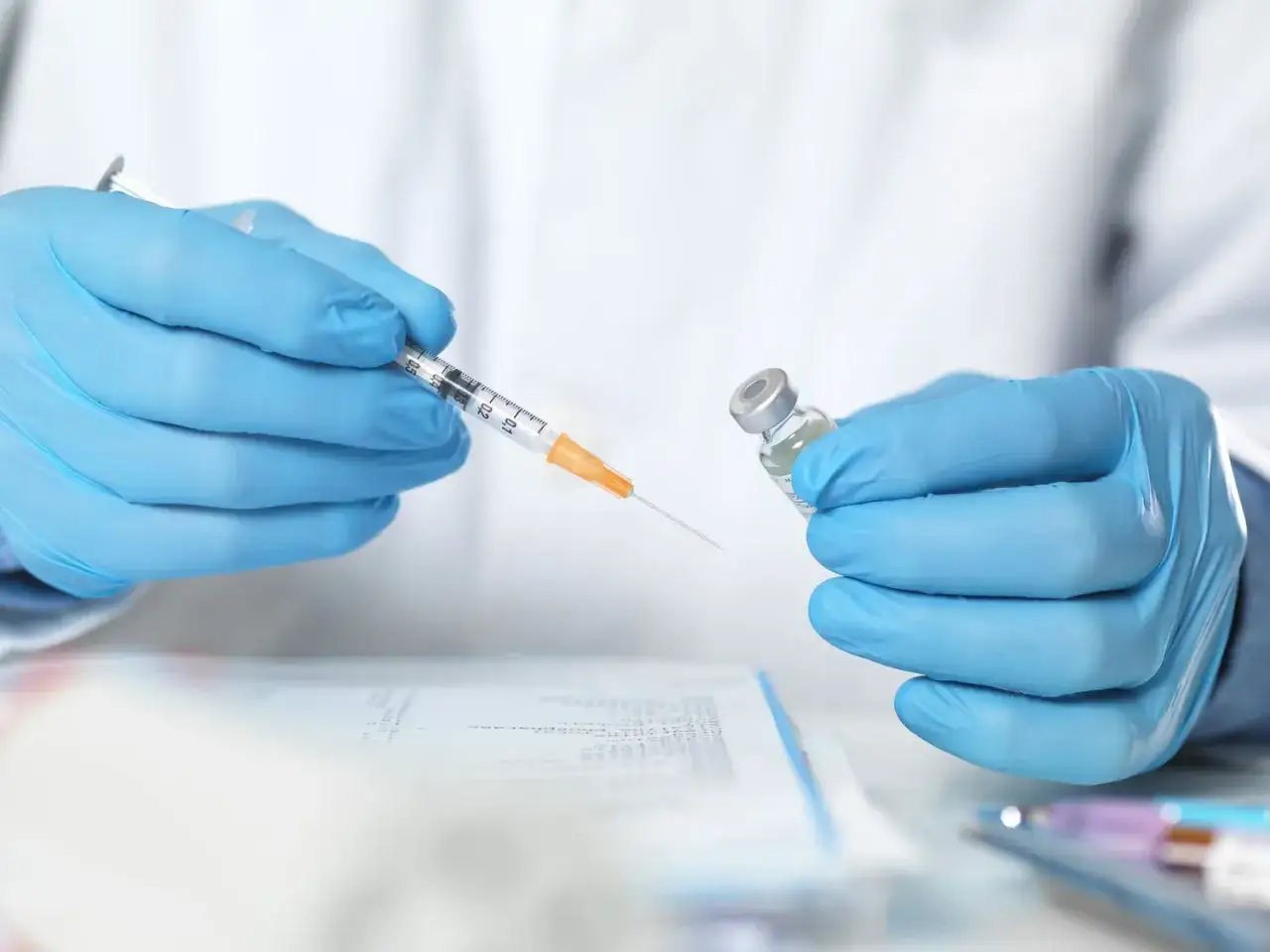 Blå handskar förbereder en spruta med vaccin. En viktig del av vaccination i Peru.