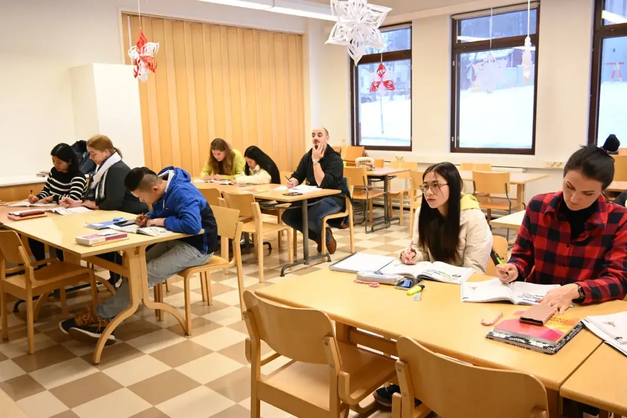 Elever deltar i kompetensutveckling och utbildning i ett klassrum. De sitter vid bord och skriver i b&ouml;cker.