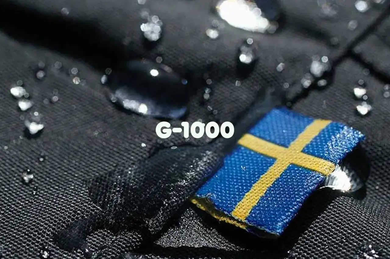 Wassertropfen perlen auf schwarzem Stoff ab, daneben ein kleines schwedisches F&auml;hnchen mit der Aufschrift 