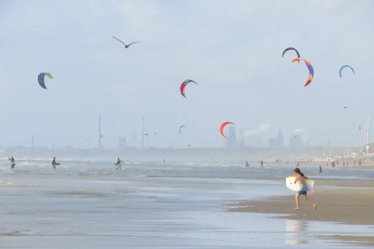 Chłopiec z deską biegnie po plaży, kitesurferzy na falach i kolorowe latawce na niebie. Tak, czy w Holandii jest morze!
