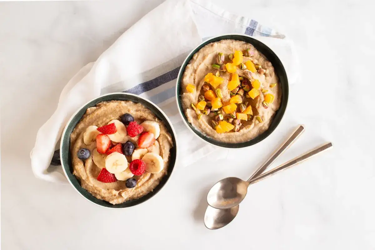 Dos tazones de crema de arroz, uno con frutas y otro con pistachos y albaricoques. ¡Cuidado, la crema de arroz engorda si no se consume con moderación!
