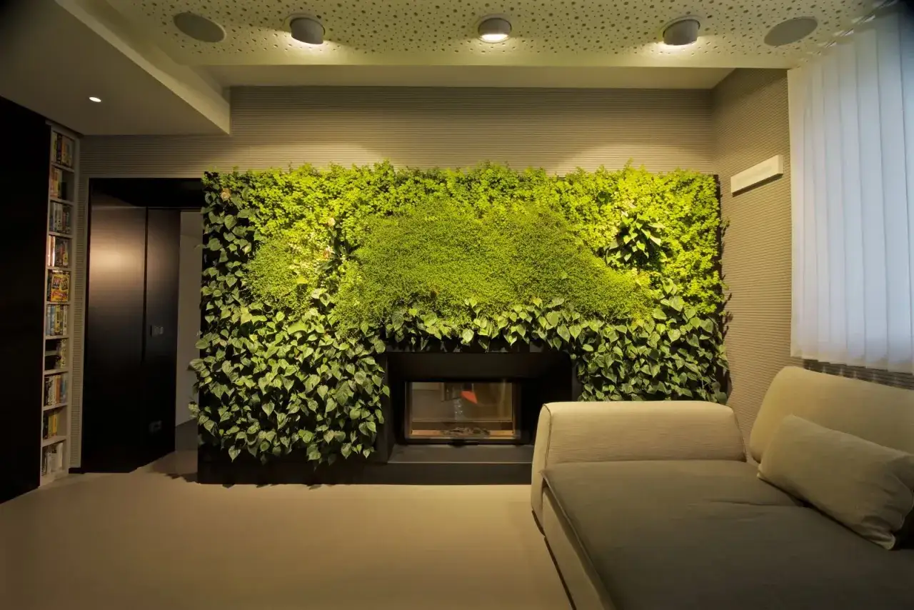 Un camino moderno incorniciato da una parete verde lussureggiante, un vero e proprio **stile urban jungle** che porta la natura in casa.