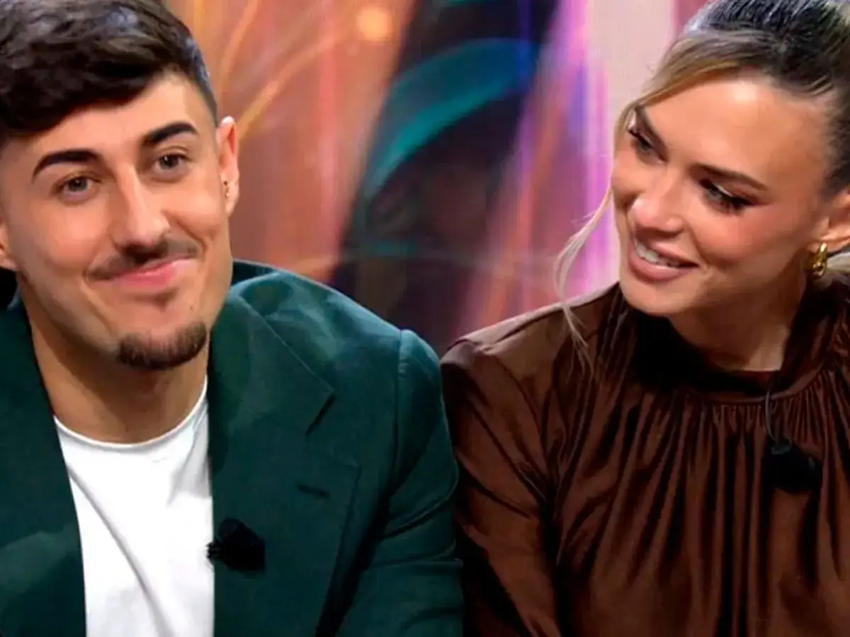 Almudena y Borja, sonriendo y mirando hacia un lado. &Eacute;l lleva un traje verde y ella un vestido marr&oacute;n.