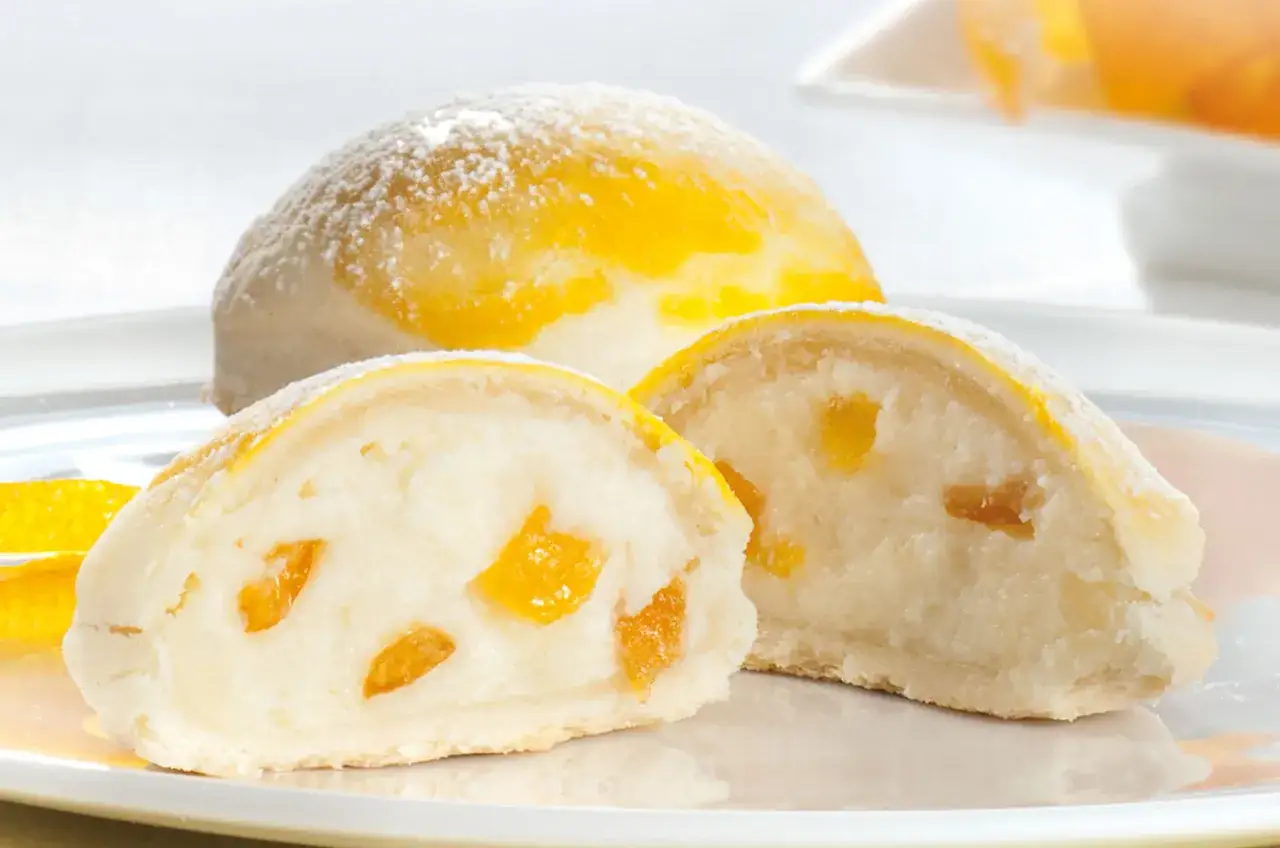 Sfogliatella frolla con ripieno cremoso e canditi d'arancia, spolverata di zucchero a velo.