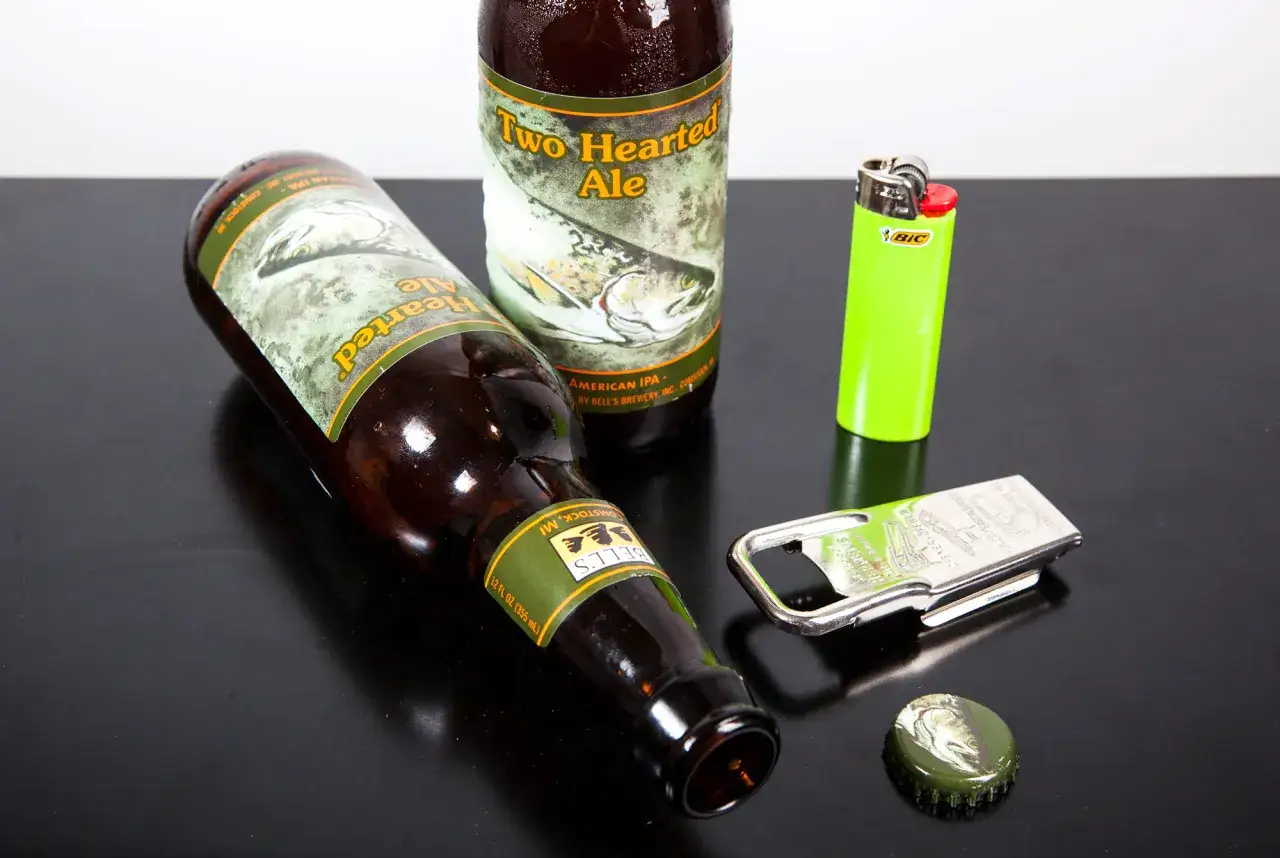 Dwie butelki piwa Two Hearted Ale, zapalniczka i otwieracz. Jak otworzyć piwo bez otwieracza? Może zapalniczka pomoże?