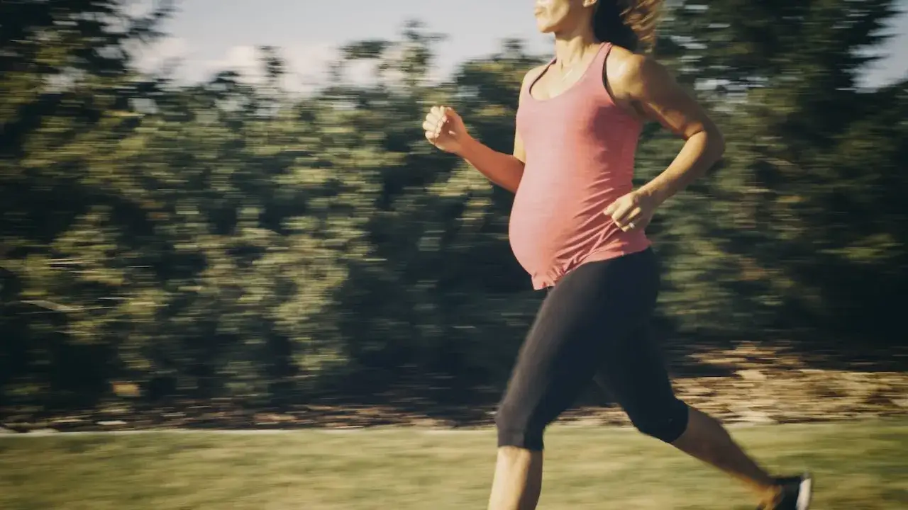 Eine schwangere Frau joggt im Freien, um fit zu bleiben.