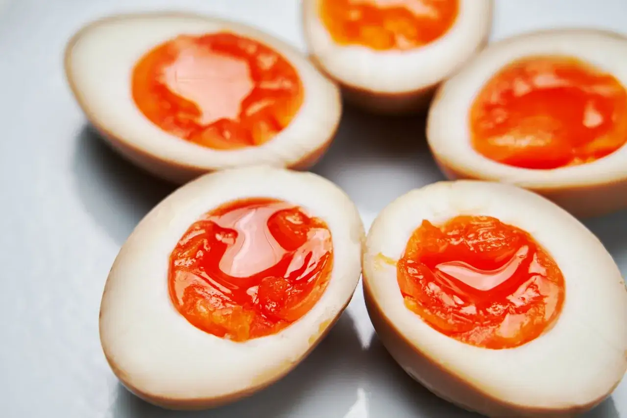 Pięć przekrojonych jajek na twardo z płynnym, pomarańczowym żółtkiem. Idealne do ramen, jak nitamago.