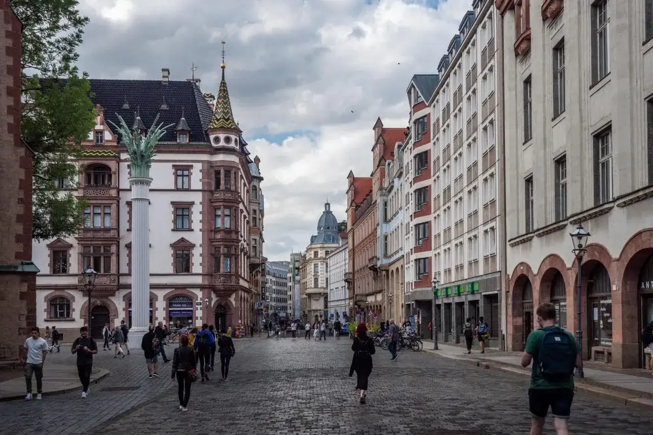 Spacerem po brukowanej ulicy w Lipsku, mijając zabytkowe kamienice i ludzi. Ta trasa zachwyca architekturą.