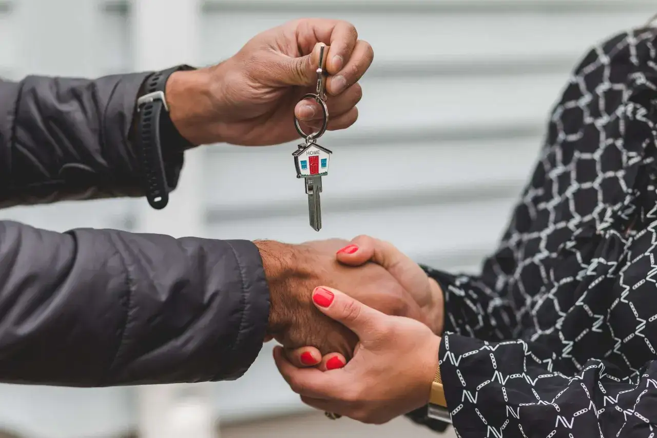 Entrega de llaves con llavero de casa. Un apret&oacute;n de manos simboliza el fin de un proceso, quiz&aacute;s una notificaci&oacute;n de lanzamiento desahucio resuelta.