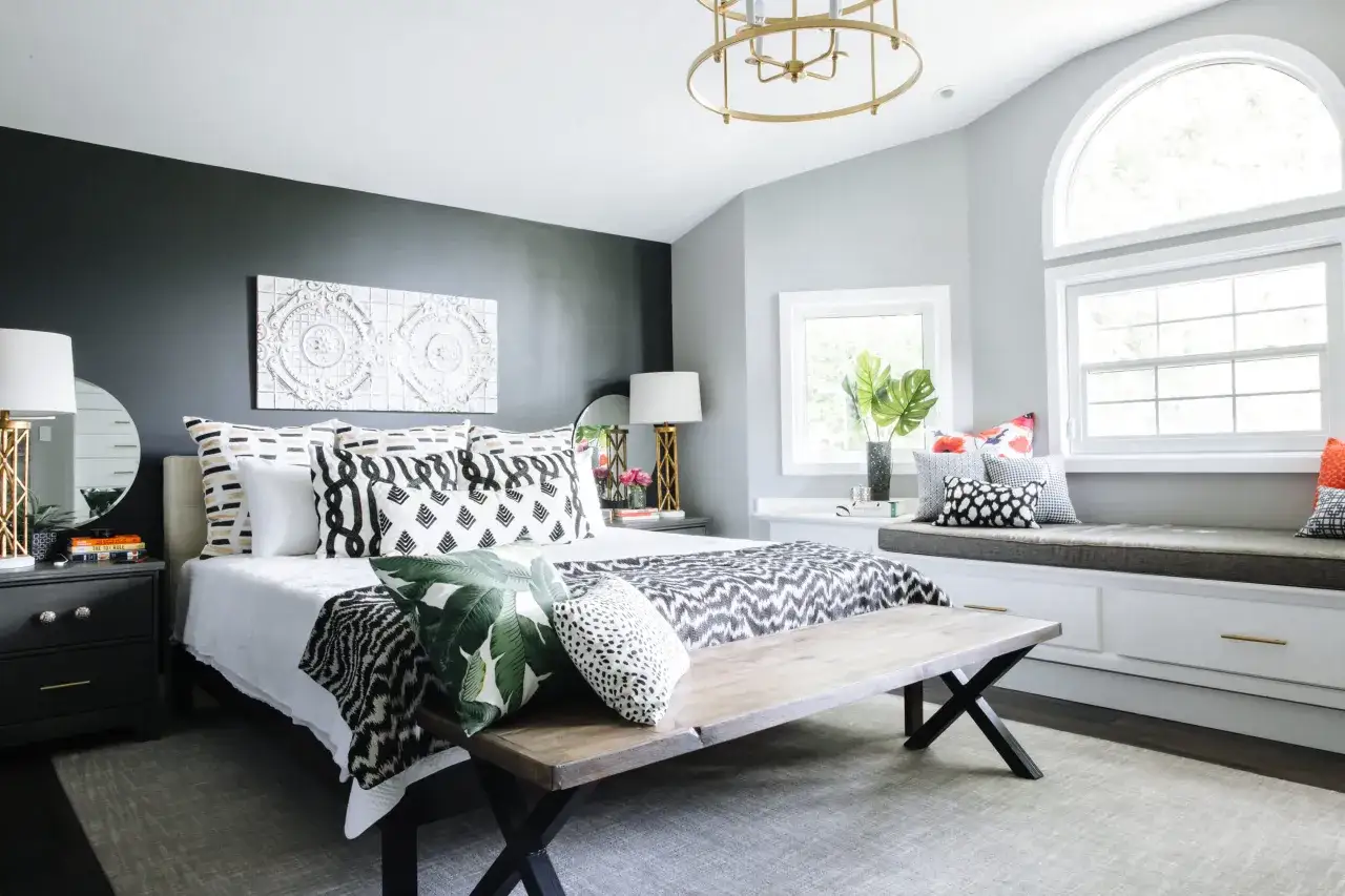 A chic bedroom makeover on a budget, featuring a dark accent wall, patterned bedding, and a cozy window seat.