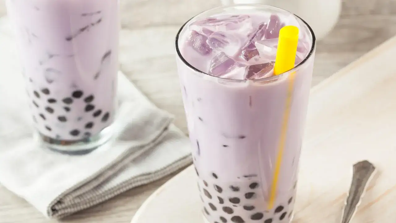 Fioletowe bubble tea z tapioki, orzeźwiający nap&oacute;j z lodem i ż&oacute;łtą słomką.