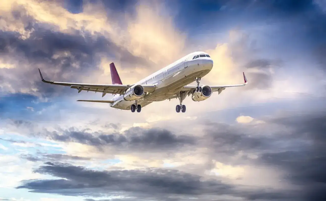 Samolot linii nouvelair wznosi się na tle dramatycznego, chmurnego nieba, gotowy do podróży.