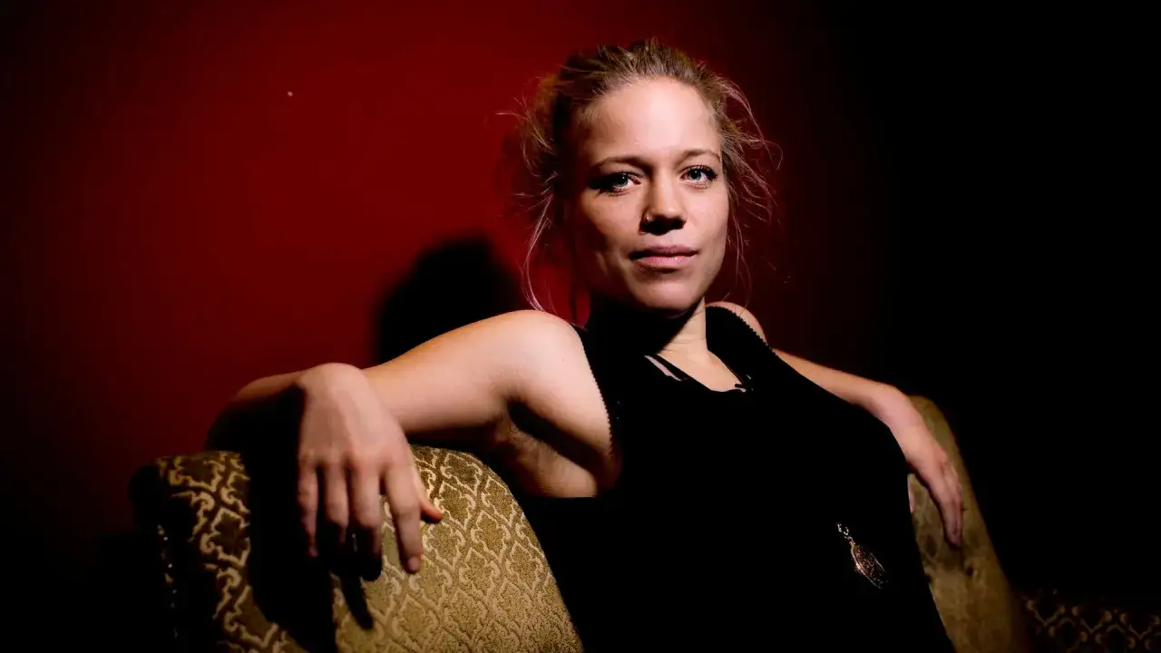 Olivia Bergdahl sitter i en soffa med en mörk bakgrund.