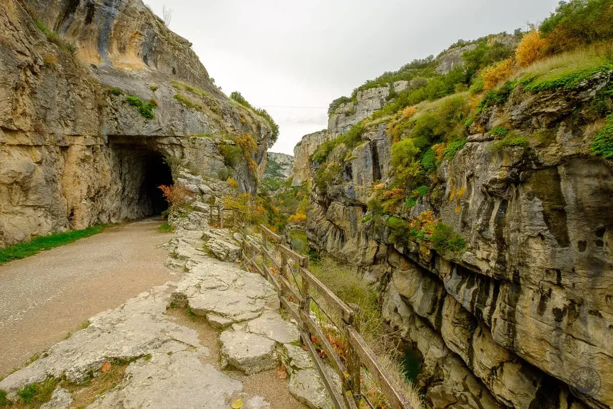 Sendero que se adentra en la foz de Lumbier, con un túnel a la izquierda y un barranco a la derecha.