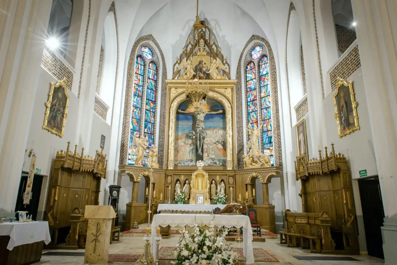 Ołtarz główny kościoła z krucyfiksem i witrażami. Darowizna na cele kultu religijnego wspiera piękno tego miejsca.