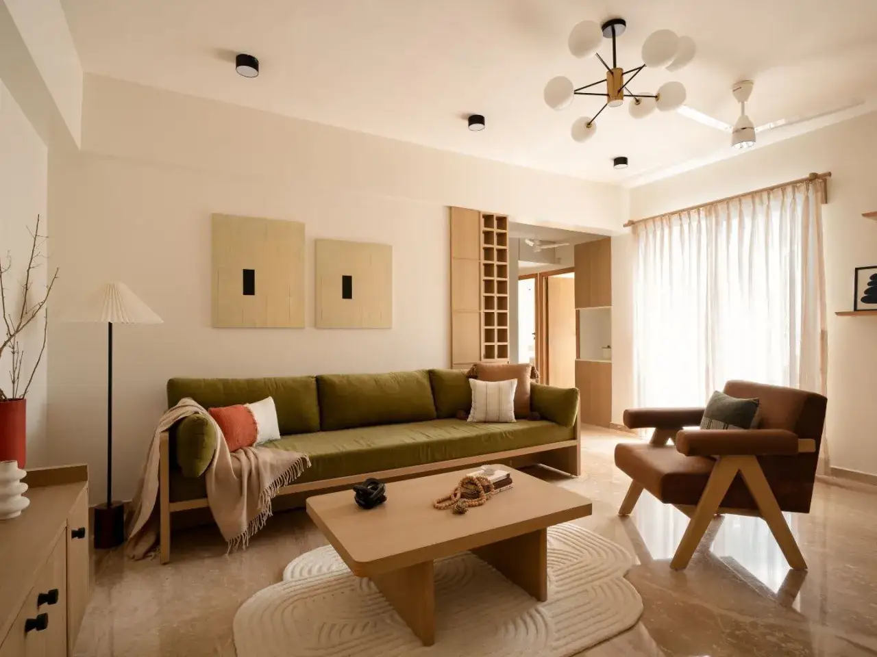 Soggiorno in stile Japandi con divano verde, poltrona in pelle, tavolino in legno e decorazioni minimaliste.