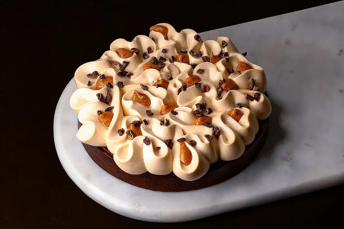 Gâteau façon snickers, une gourmandise au chocolat et caramel, garni de crème onctueuse et de éclats de cacao.