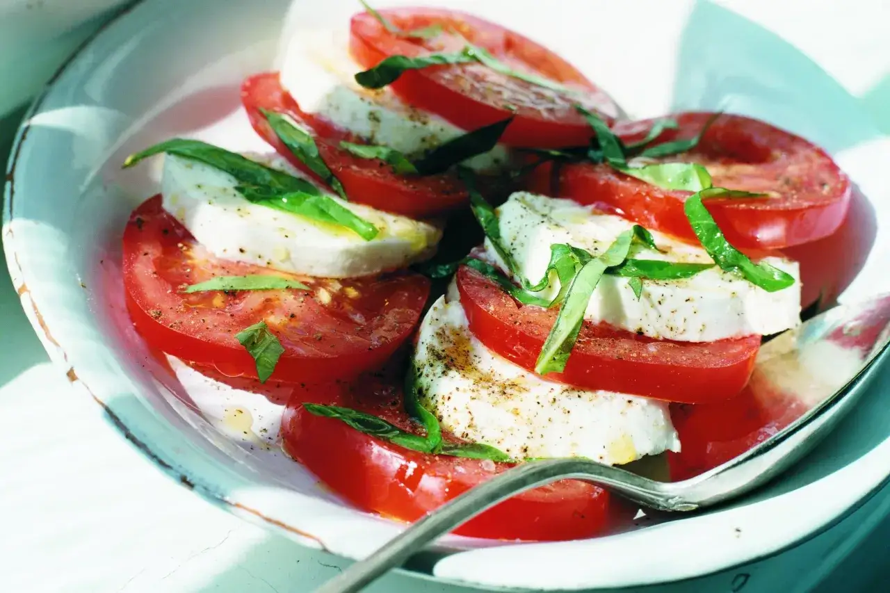 En läcker tomat sallad med färsk mozzarella och basilika, kryddad med peppar.