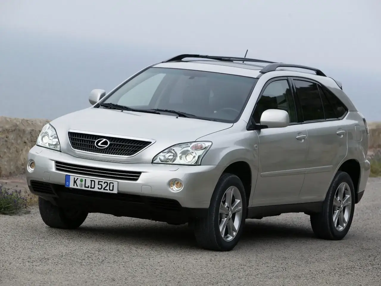 Srebrny Lexus RX 300 z 2003 roku stoi na drodze z kamiennym murem w tle.