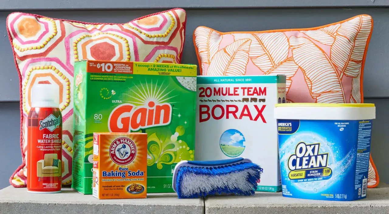 Supplies for how to clean outdoor cushions: Scotchgard, Gain detergent, Borax, baking soda, OxiClean, and a scrub brush.