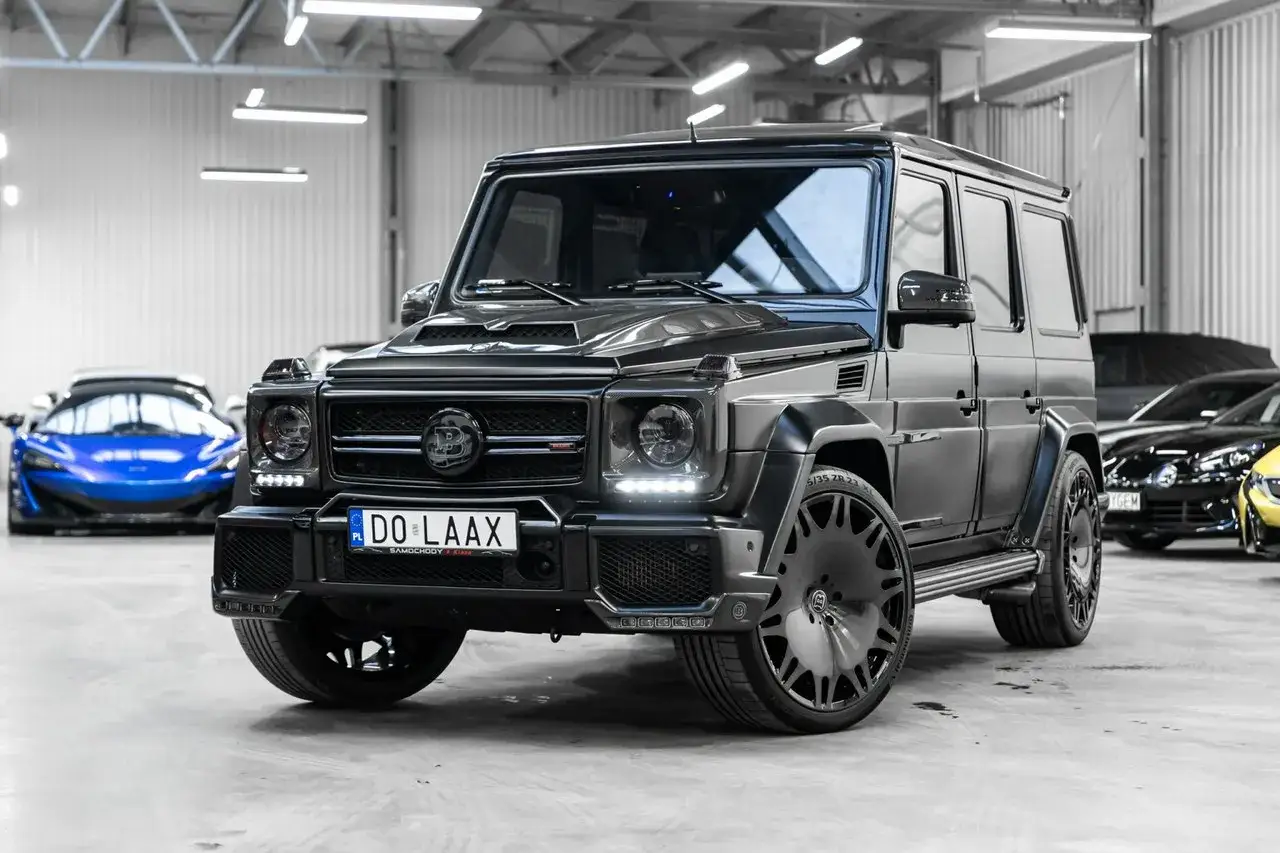 Czarny Mercedes G63 z masywnymi felgami i agresywnym body kitem, gotowy na podbój dróg. Obok błyszczy niebieski supersamochód.