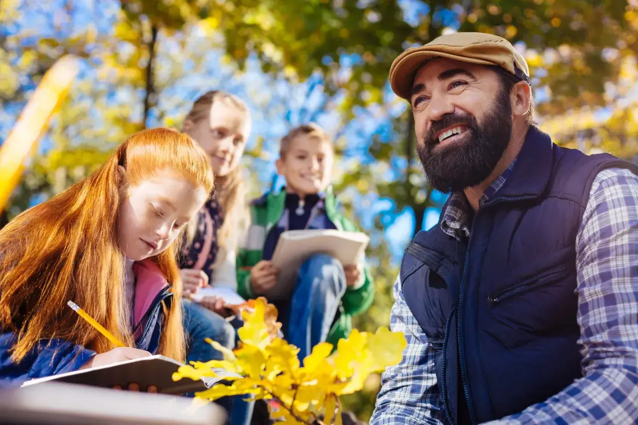 Ein Lehrer verweigert die Klassenfahrt, w&auml;hrend Kinder im Herbstlaub zeichnen.