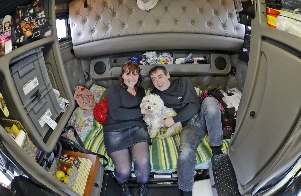 Un couple et leur chien blanc profitent d'un moment de d&eacute;tente dans la cabine d'un camion am&eacute;ricain, un espace cosy am&eacute;nag&eacute; pour la vie sur la route.