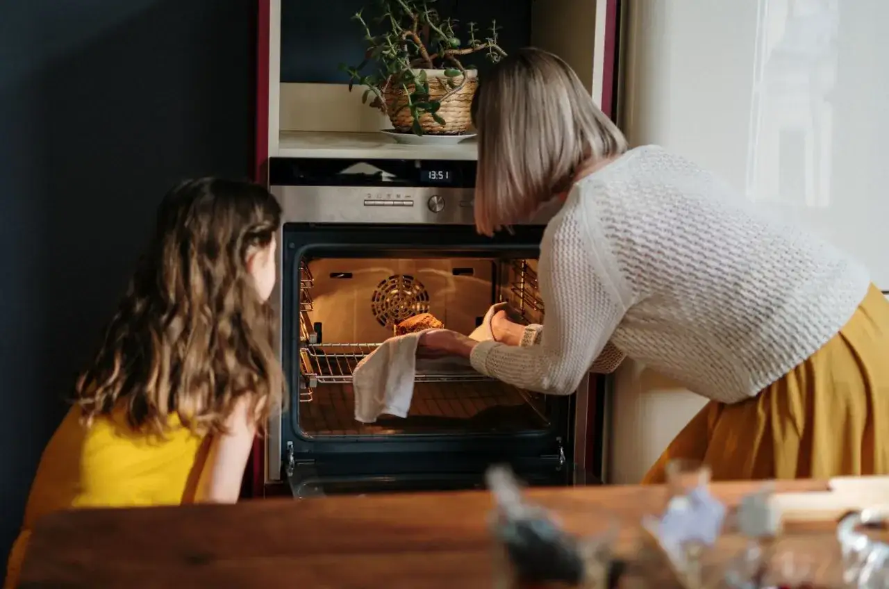 Mama i córka przygotowują pierwsze uruchomienie piekarnika, wkładając do niego ciasto.