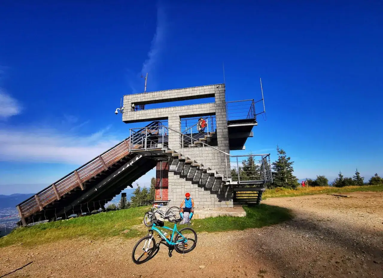 Rowerzyści odpoczywają przy wieży widokowej, gotowi na dalsze odkrywanie tras rowerowych w Beskidach.