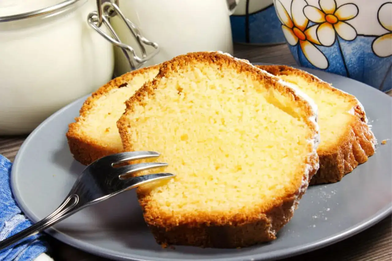 Tranches de gâteau moelleux sur une assiette grise, parfaites pour une recette gâteau facile et rapide. Une tasse décorée et un pot en verre sont en arrière-plan.