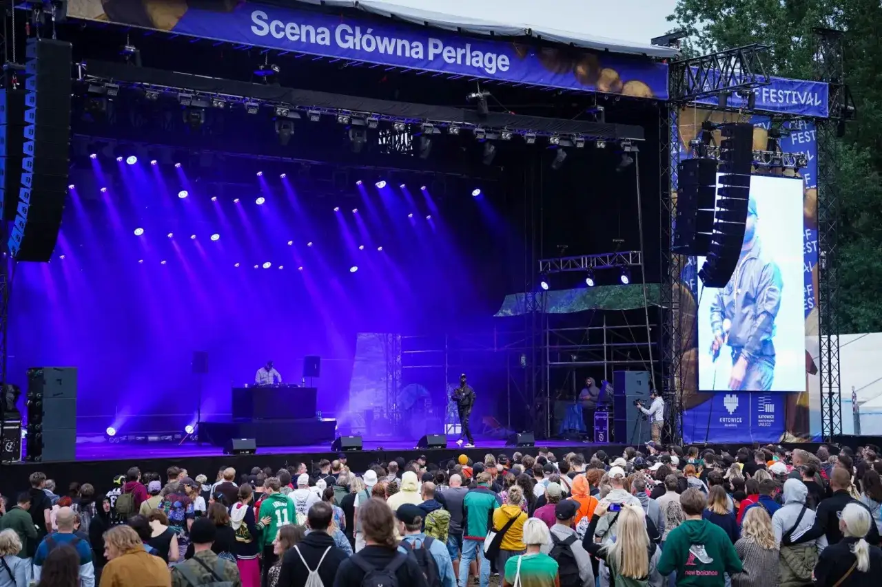 Tłum ludzi na koncercie podczas festiwalu w Katowicach. Na scenie artyści, a nad nimi wielki ekran z transmisją.